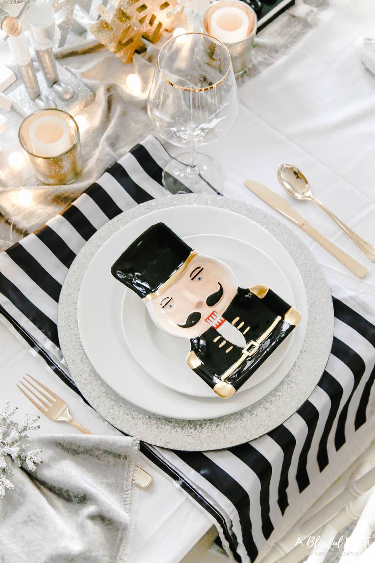 Black and gold nutcracker plate sitting on top of white dishes