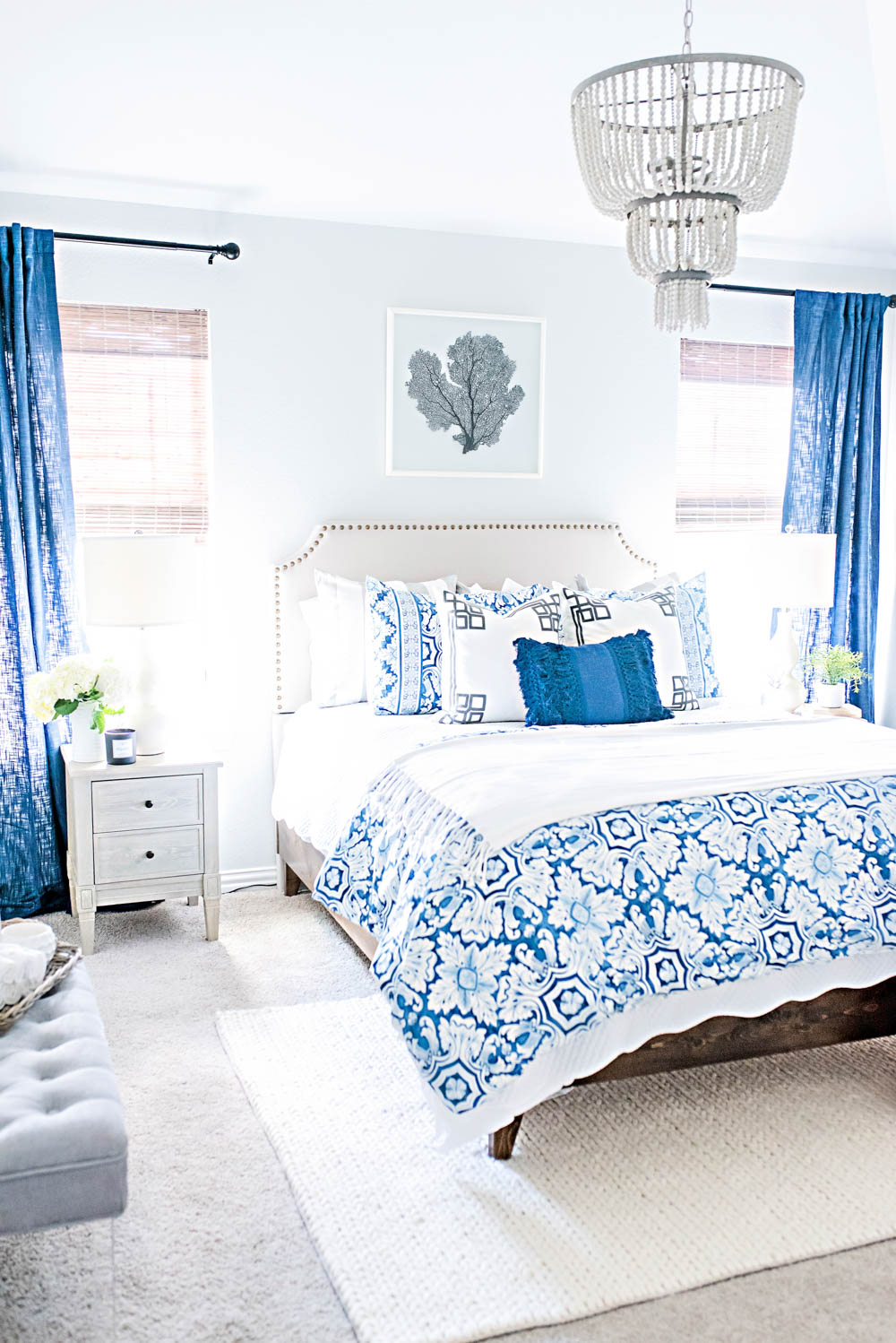 Blue and white bedding with a tiered wood bead chandelier in this guest bedroom