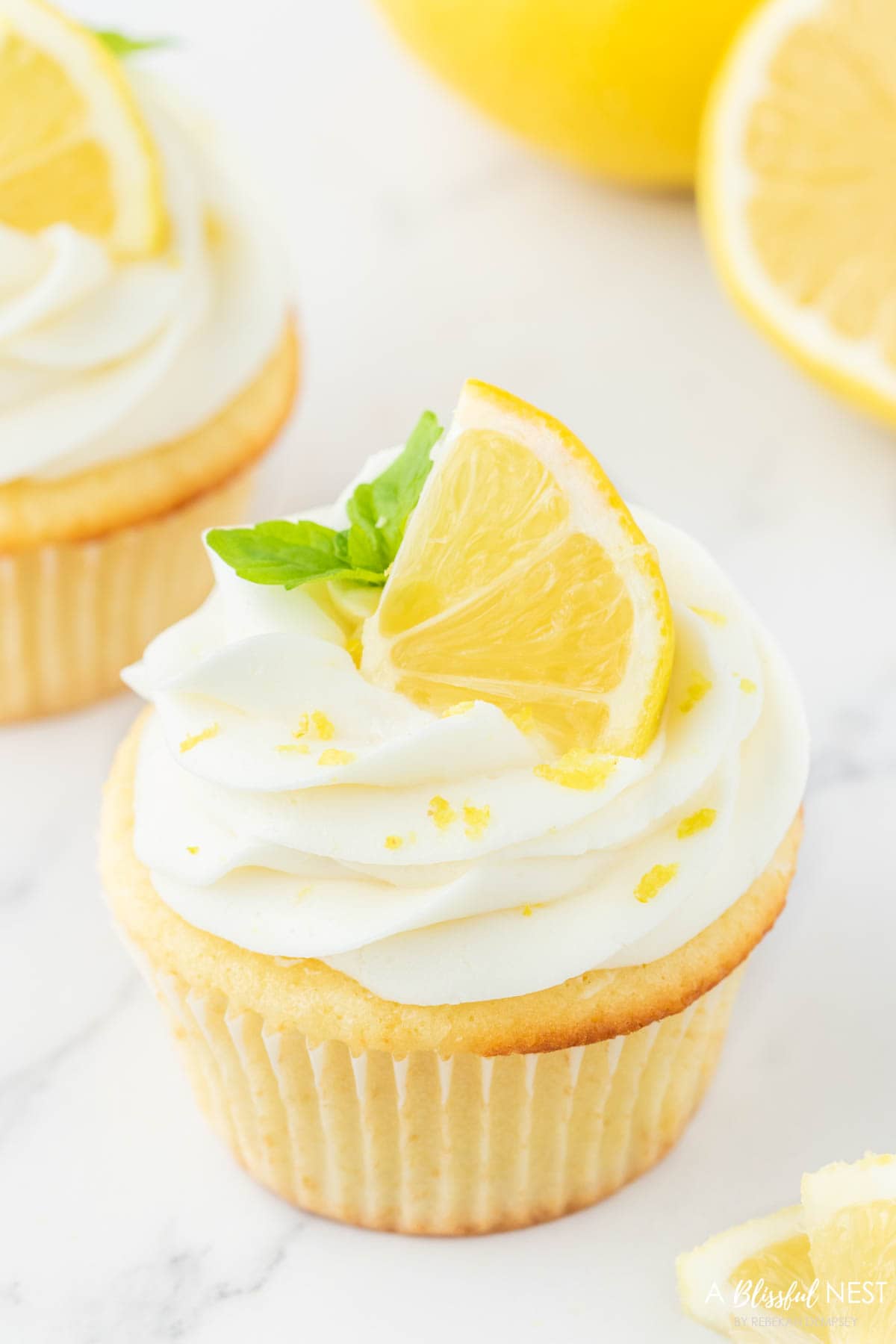 Lemon cupcake with lemon slice and mint ontop.