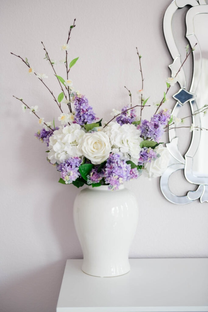 Lilac and white roses in a tall white ginger jar vase