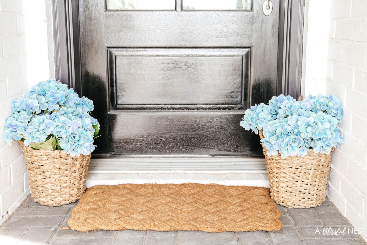 2 baskets on either side of front door filled with light blue faux hydrangeas.