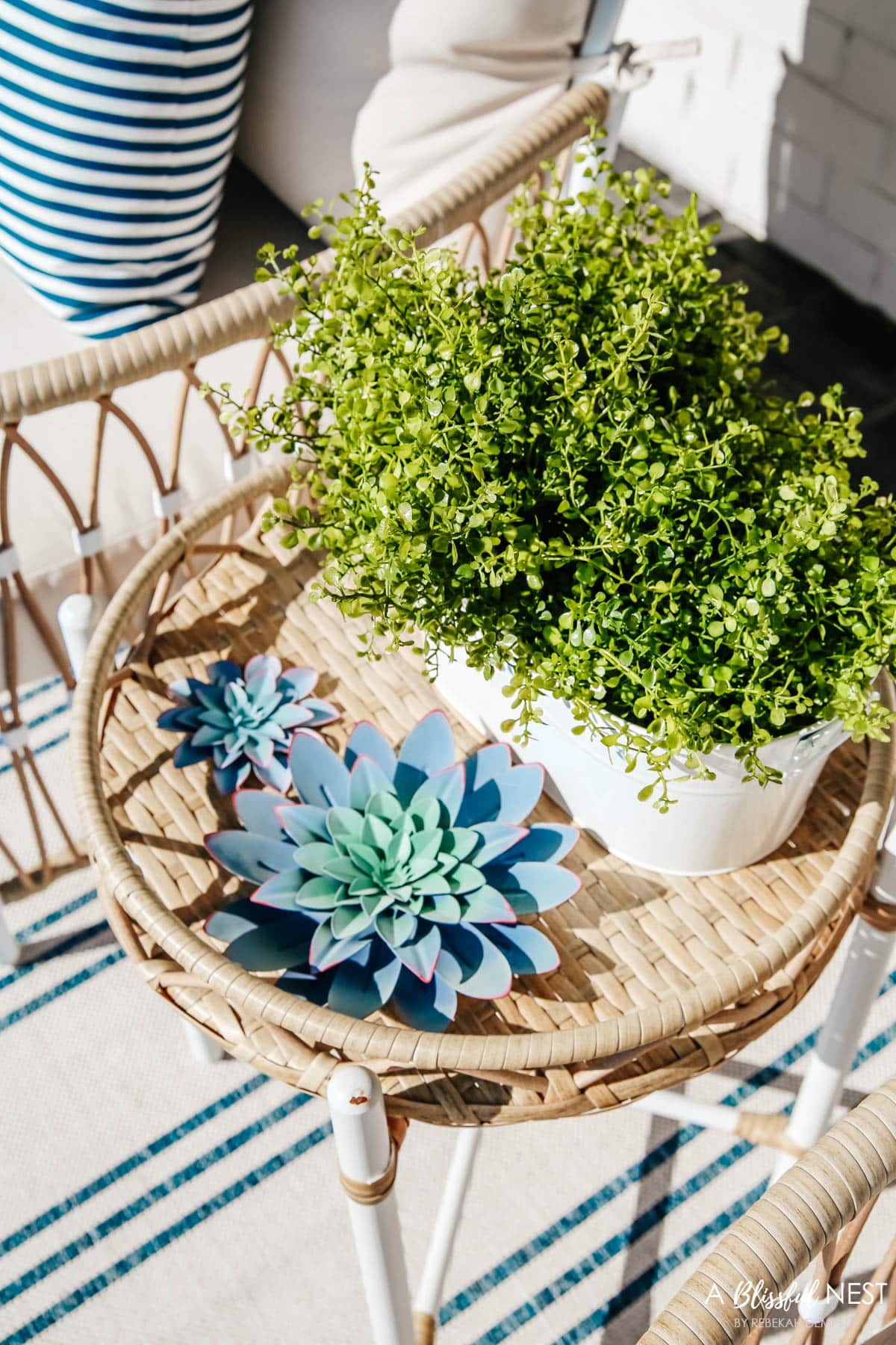 small white bucket filled with faux ferns and 2 metal succulent decor on side table for front porch