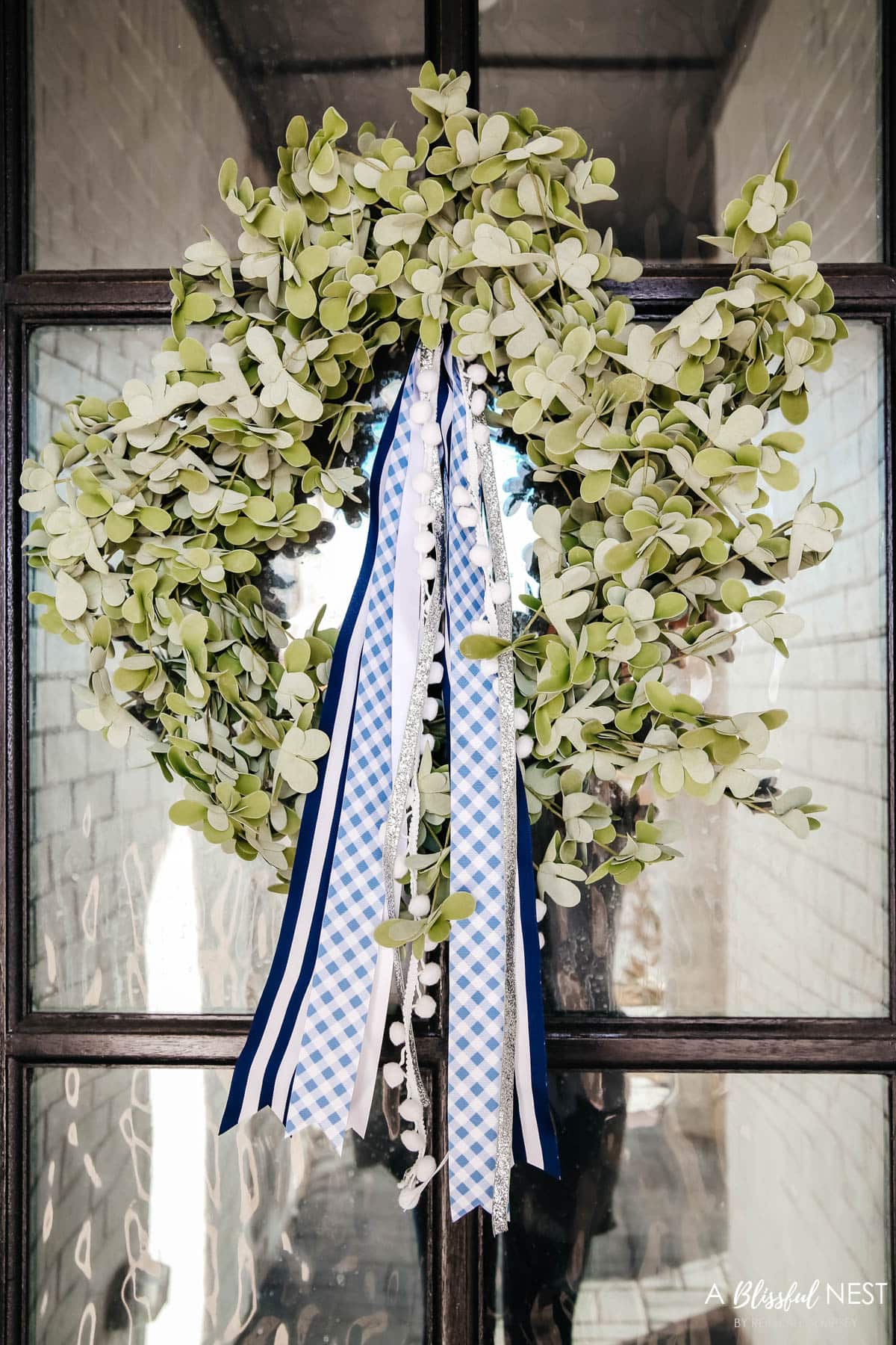 Eucalyptus wreath with blue and white ribbons tied at top for color.