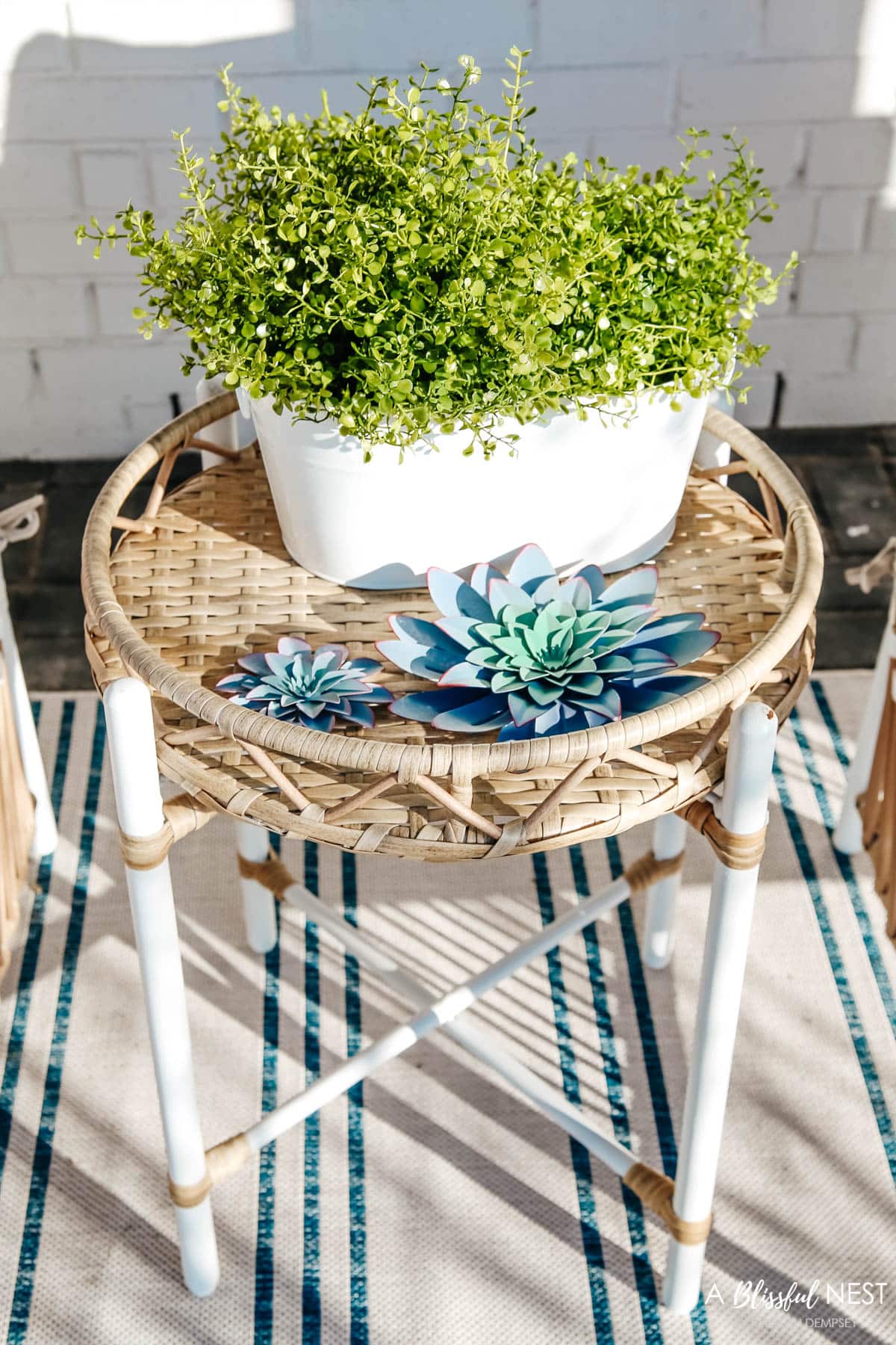 small white bucket filled with faux ferns and 2 metal succulent decor on side table for front porch