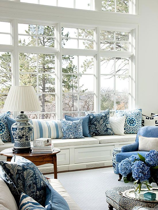 Image of a white sofa with various shades of blue pillows. The pillows are arranged in a neat and stylish manner, with some being solid-colored and others patterned. The pillows provide a nice contrast to the white sofa, making it a cozy and inviting seating area.