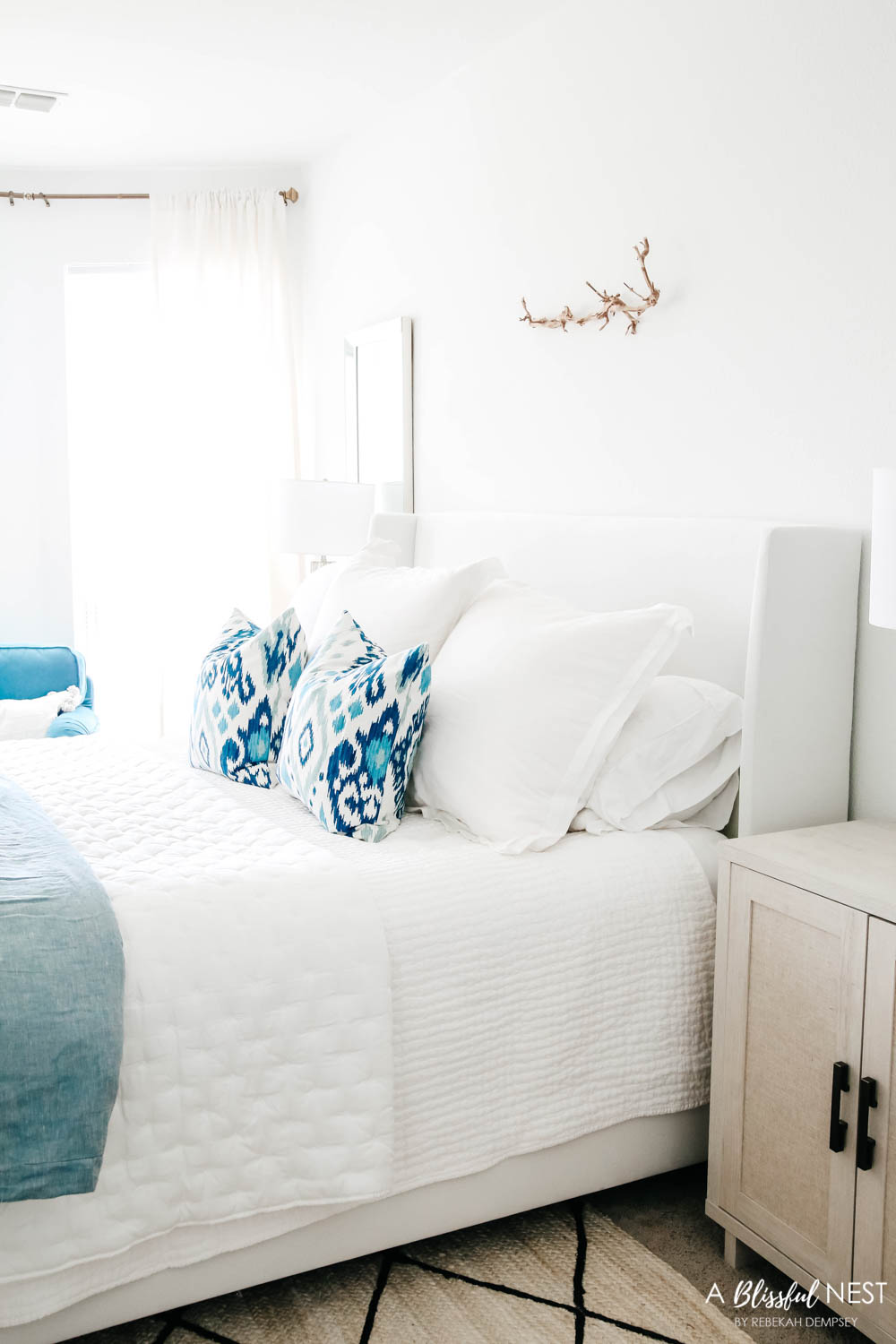 Blue and white bedding matched with a white upholstered bed.