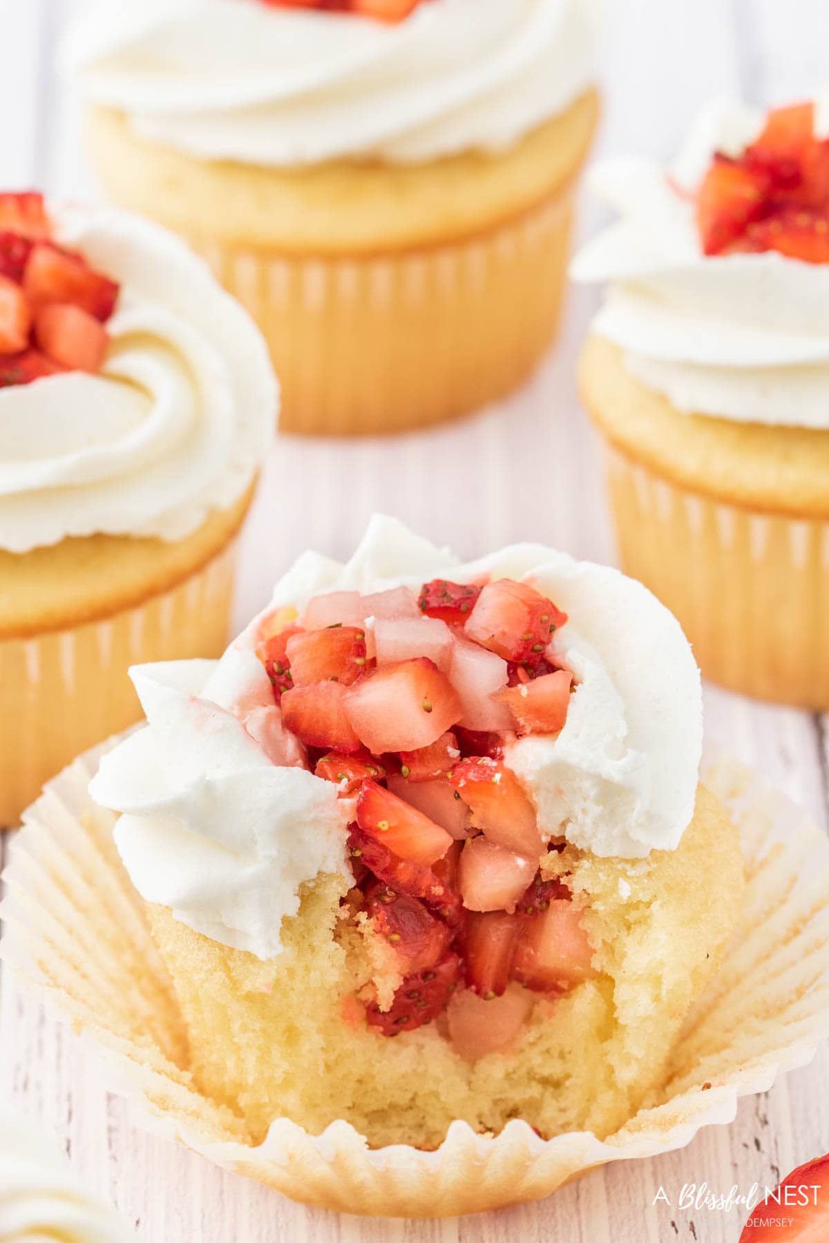 A cupcake cut open to show the strawberry filling inside.