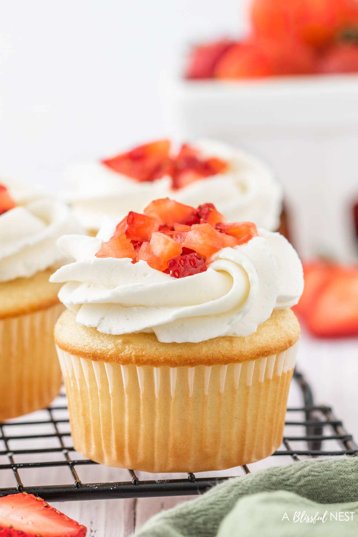 Cupcake with cut strawberries and buttercream frosting.