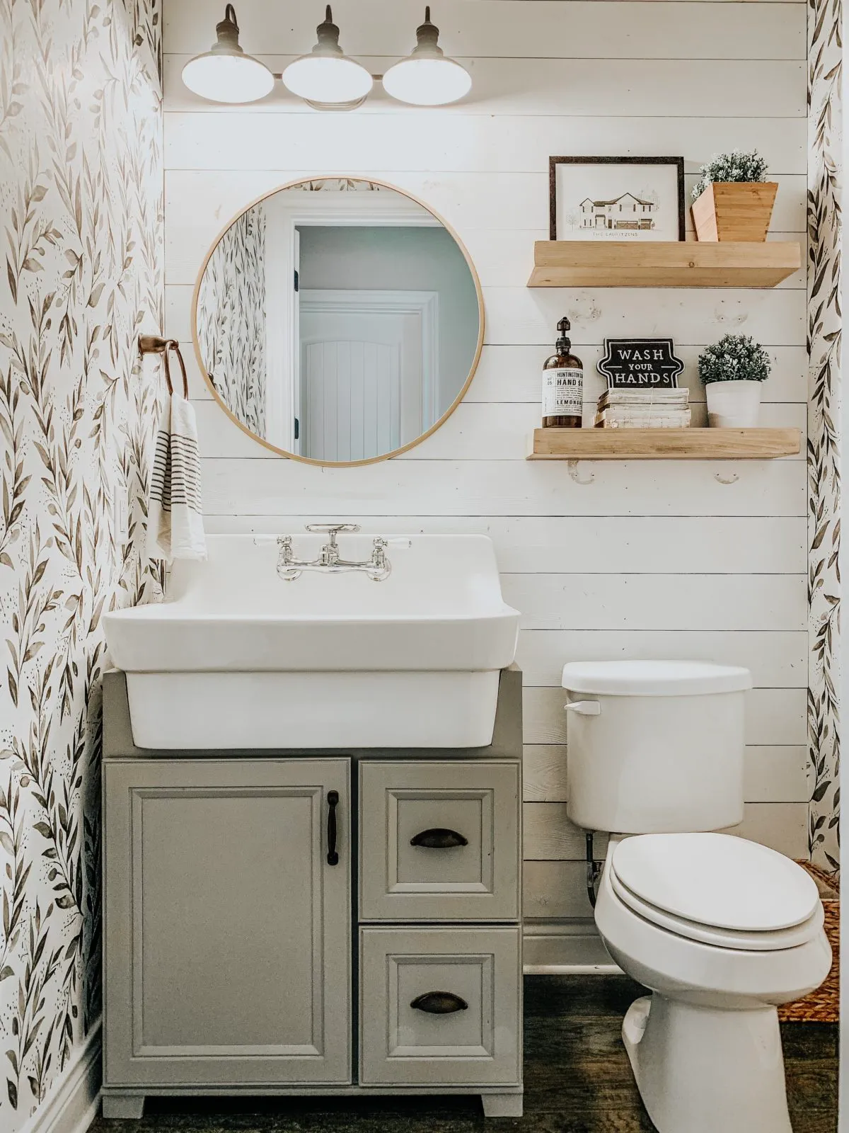 Sage green cabinet with apron sink, patterned wallpaper with sage green leaves, shiplap wall. 