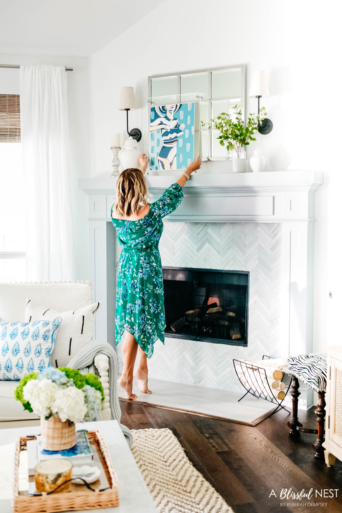 styling a fireplace mantel with artwork, mirror, flowers, and candlesticks
