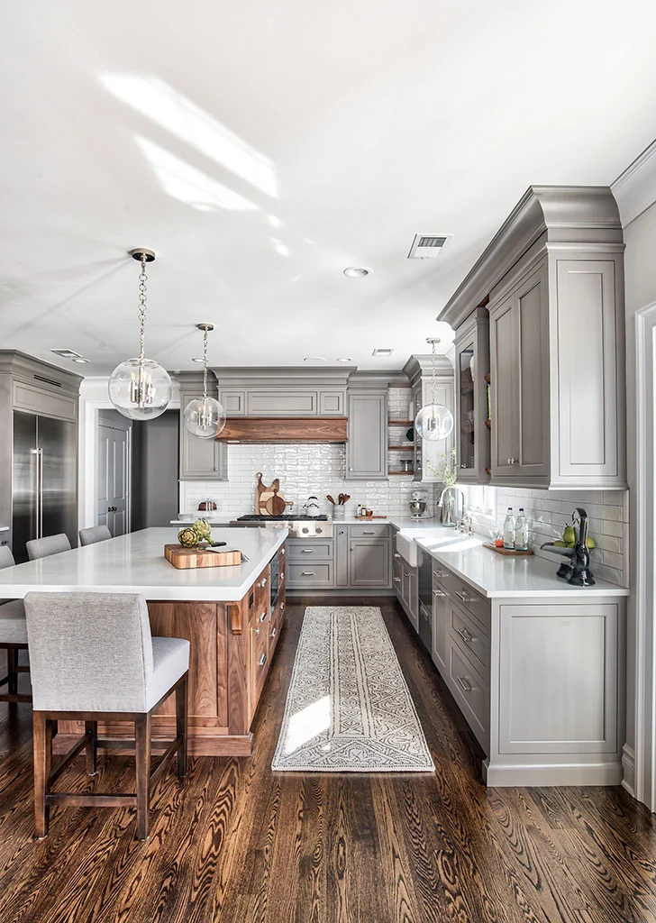 Grey kitchen cabinets with honey oak colored wood accents for the kitchen island on hood. 