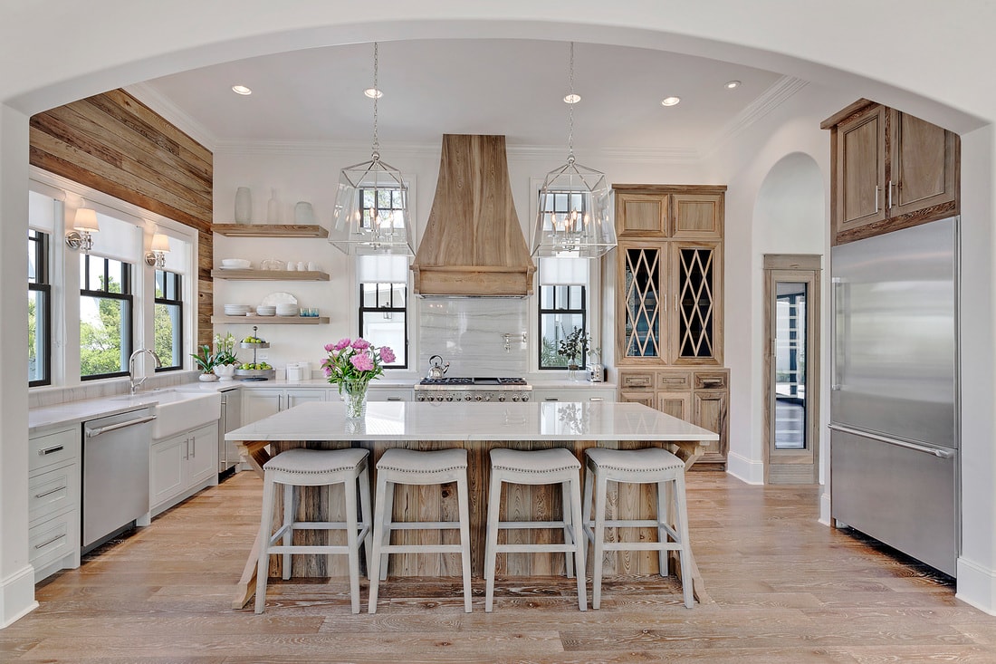 White kitchen with wood hood and natural wood shiplap wall above the sink with a window.