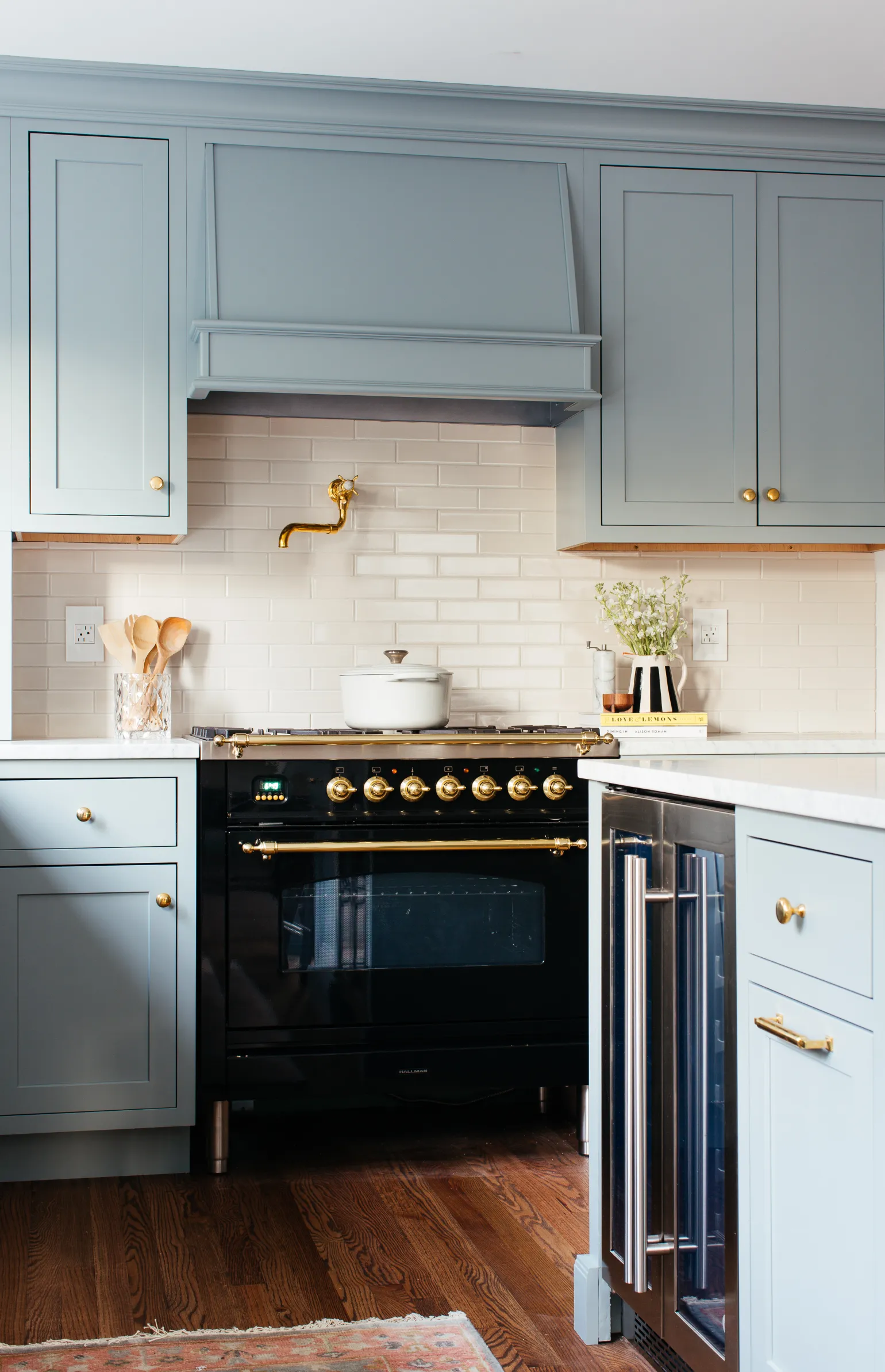 medium shade blue gray kitchen cabinet color with brass cabinet hardware and white subway tile 