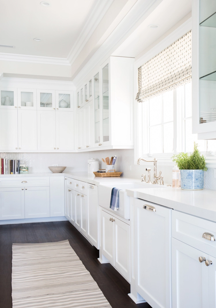 White kitchen cabinets with chrome hardware and white farmhouse sink