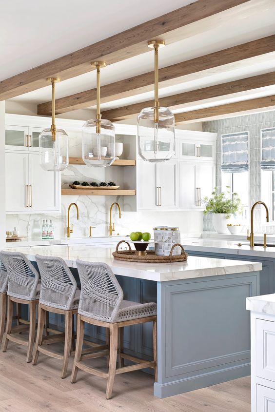 Light blue kitchen island paint color with white perimeter cabinets, gold faucets, woven barstools