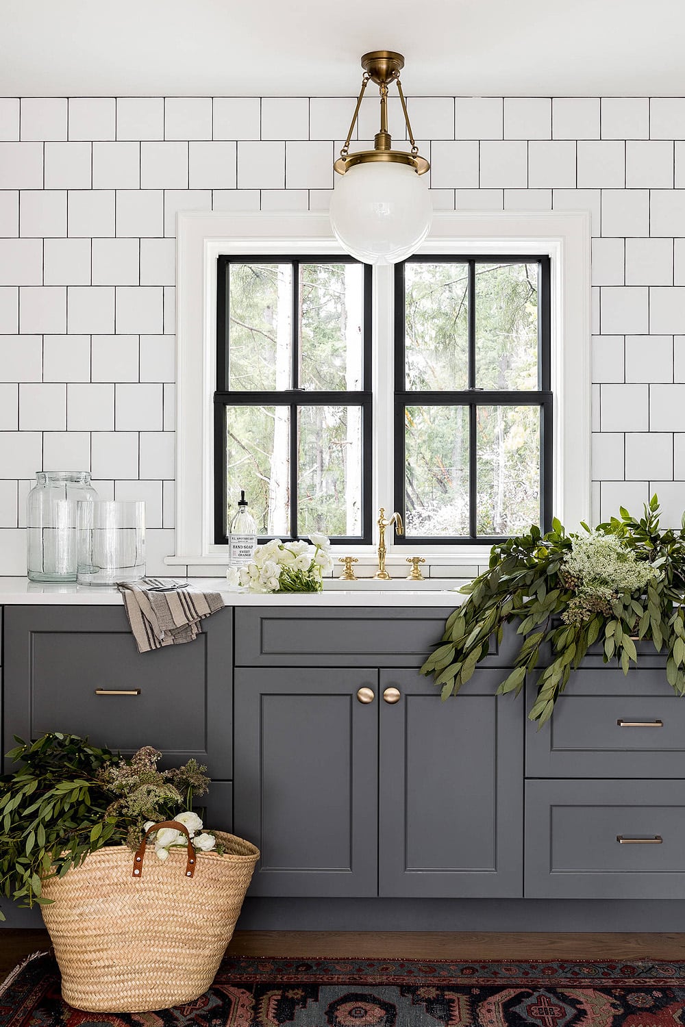 dark grey kitchen cabinets with gold cabinet hardware, white square tile with dark grout.