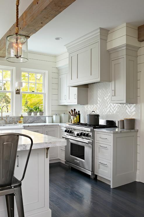 Light grey kitchen cabinets with white herringbone subway tile for backsplash
