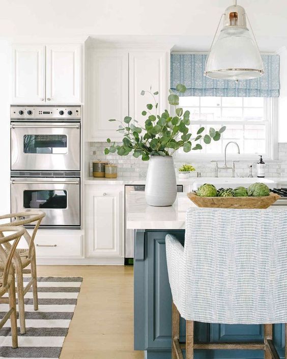 blue kitchen island with white perimeter kitchen cabinets, quartz countertops and soft blue decor accents. 