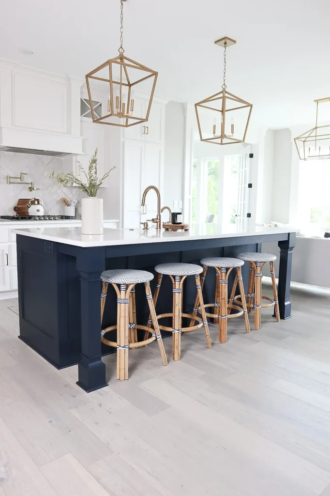 Navy blue kitchen island with all white cabinets, gold hanging lantern pendants