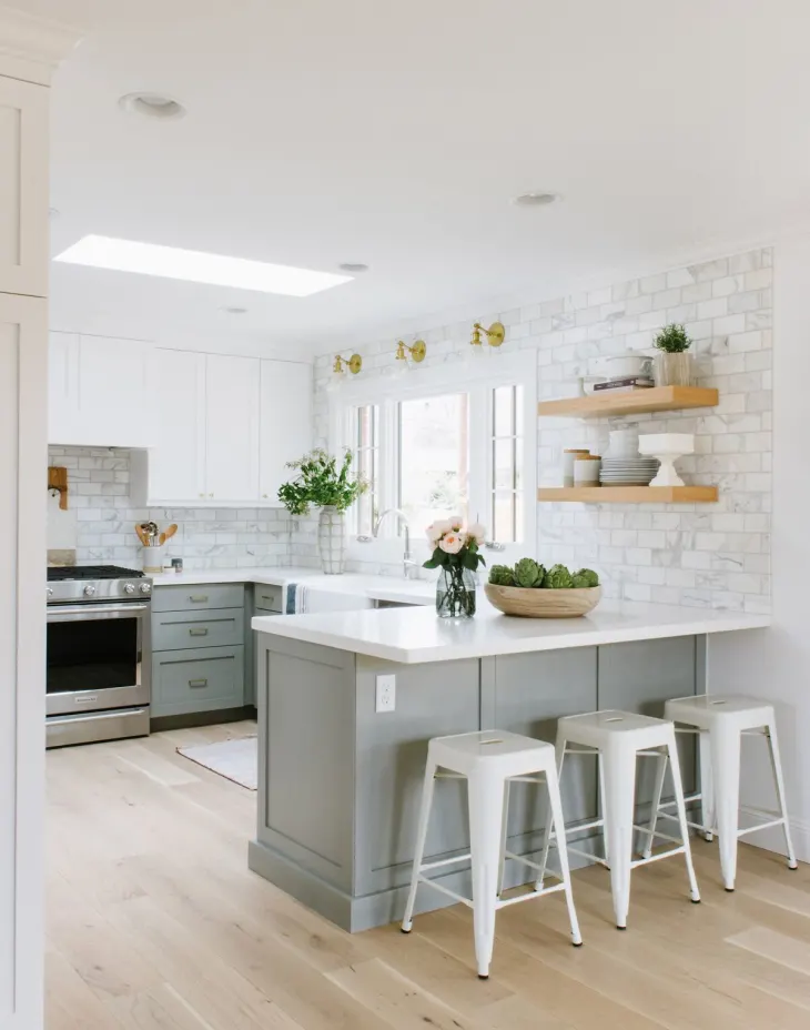 Medium gray kitchen cabinets with marble subway tiles for backsplash.