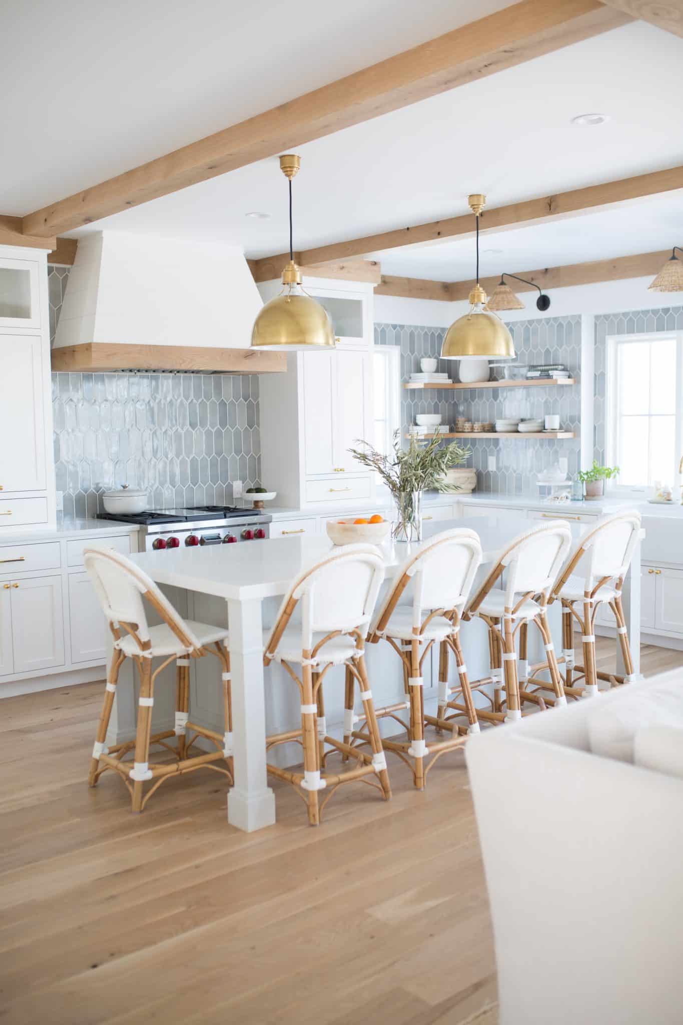 white kitchen with wood beans and matching band on edge of range hood. Serena & Lily barstools, oak flooring