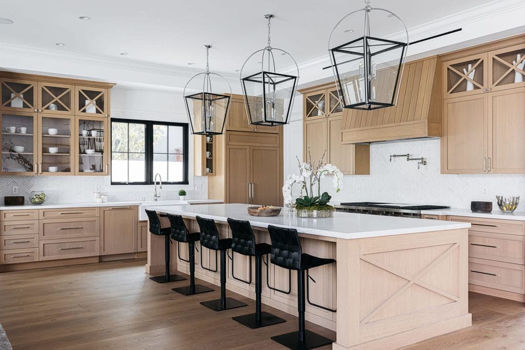 natural wood kitchen cabinets with black accents. Black lanterns, black barstools. white quartz counters