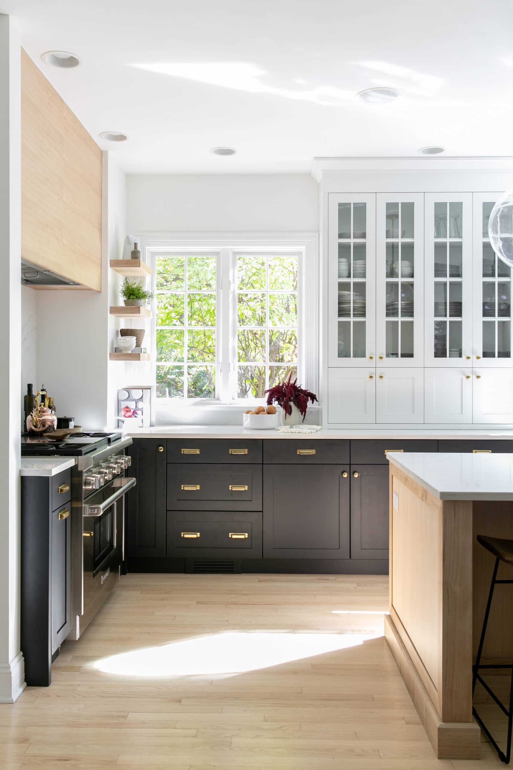 White upper cabinets with black lower cabinets in a kitchen, gold hardware.