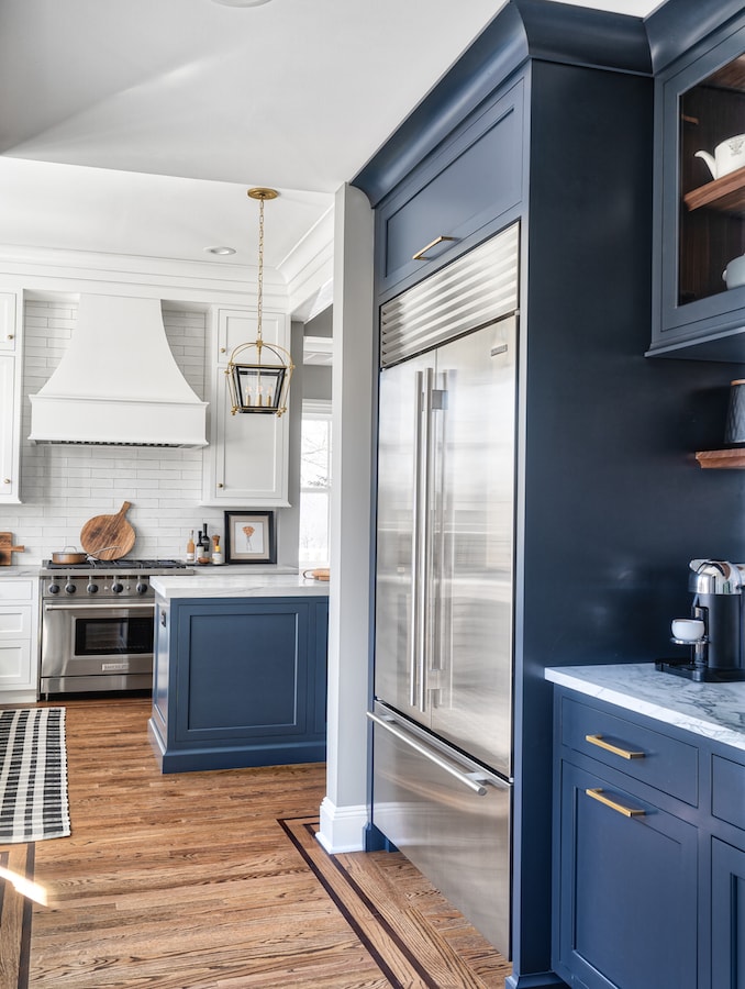 Buttlers pantry and kitchen island in a rich navy blue while rest of kitchen is white.