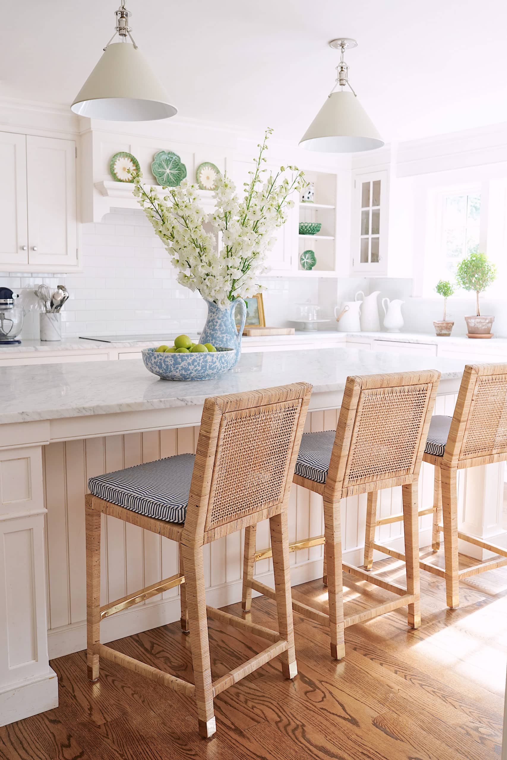 Light beige kitchen island with creamy white kitchen cabinets. Serena & Lily barstools and honey oak wood floors