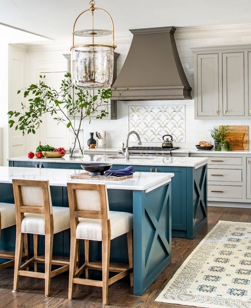 Dark turquoise blue kitchen island, dark grey range hood, light grey exterior cabinets with gold hardware