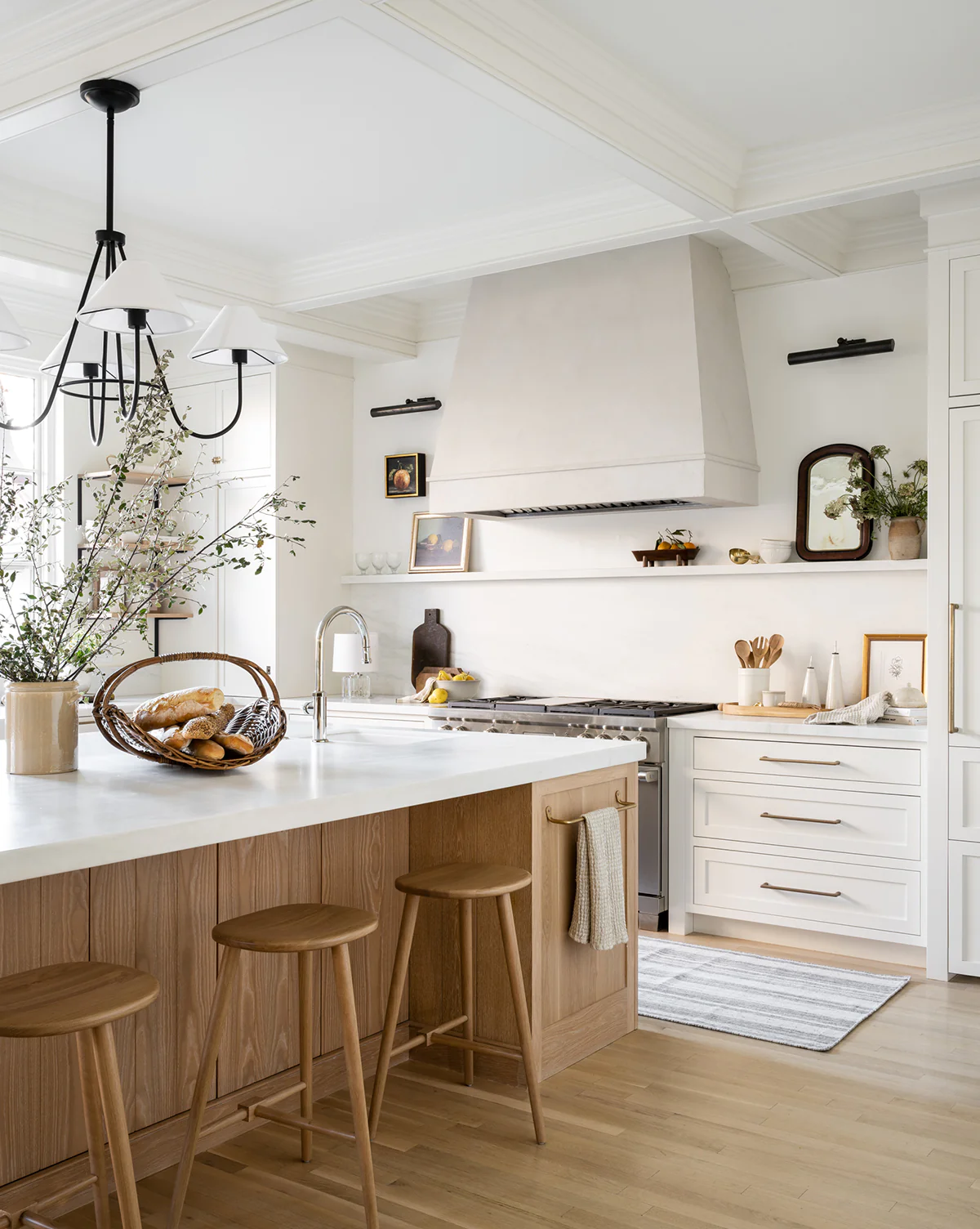 natural wood kitchen island, white kitchen with gold cabinet hardware, lighter wood flooring