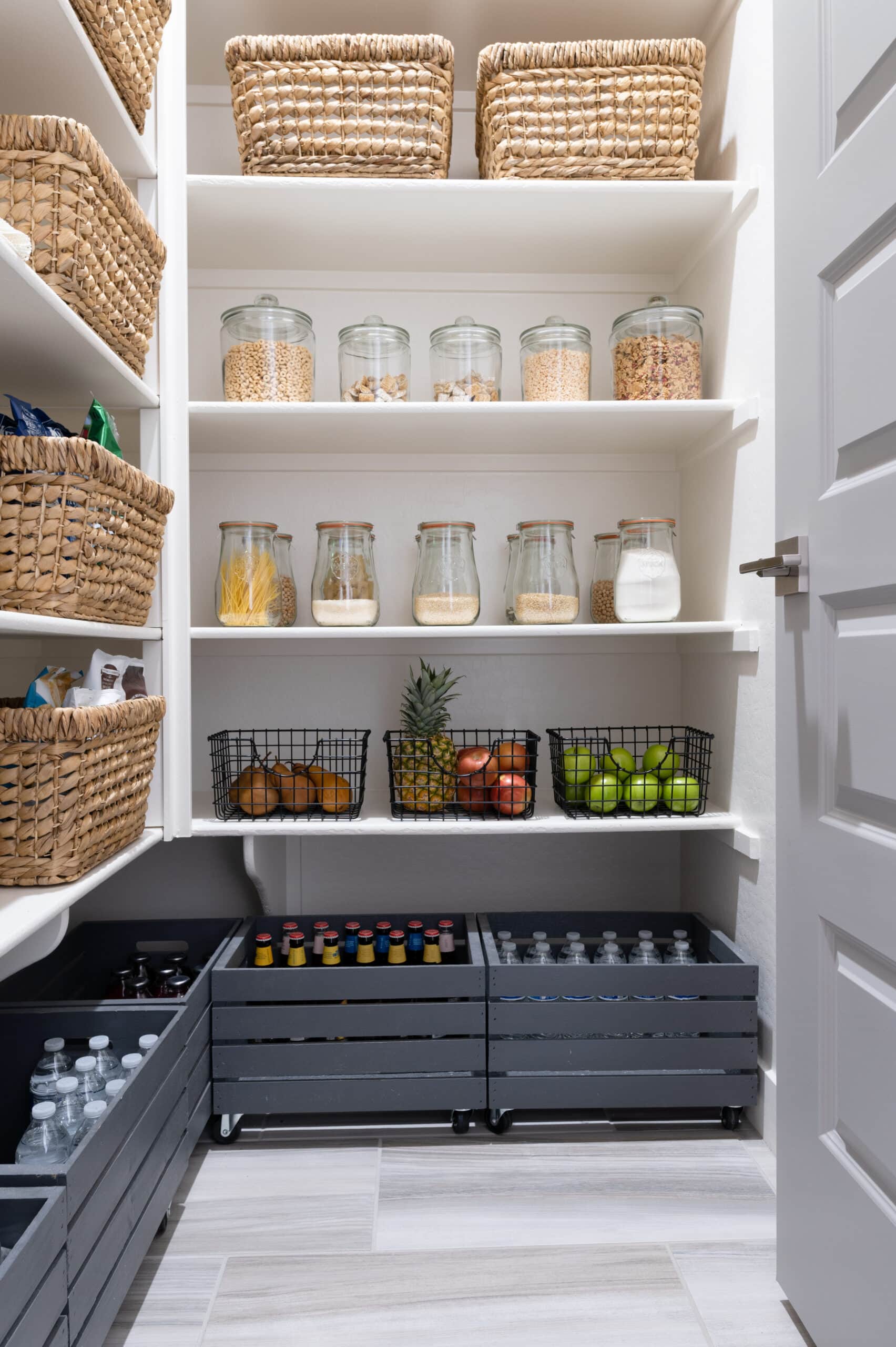 rolling carts on the bottom of the pantry for large bottles and water bottles.