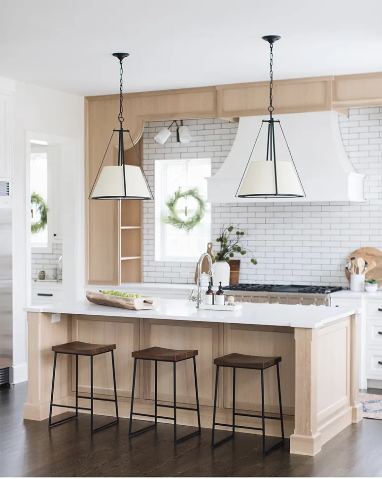 oak kitchen cabinets, white subway tile with dark grout, white range hood, dark wood barstools