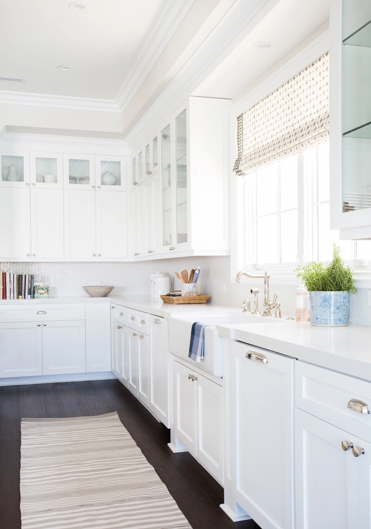 white kitchen cabinets with chrome hardware, dark wood flooring