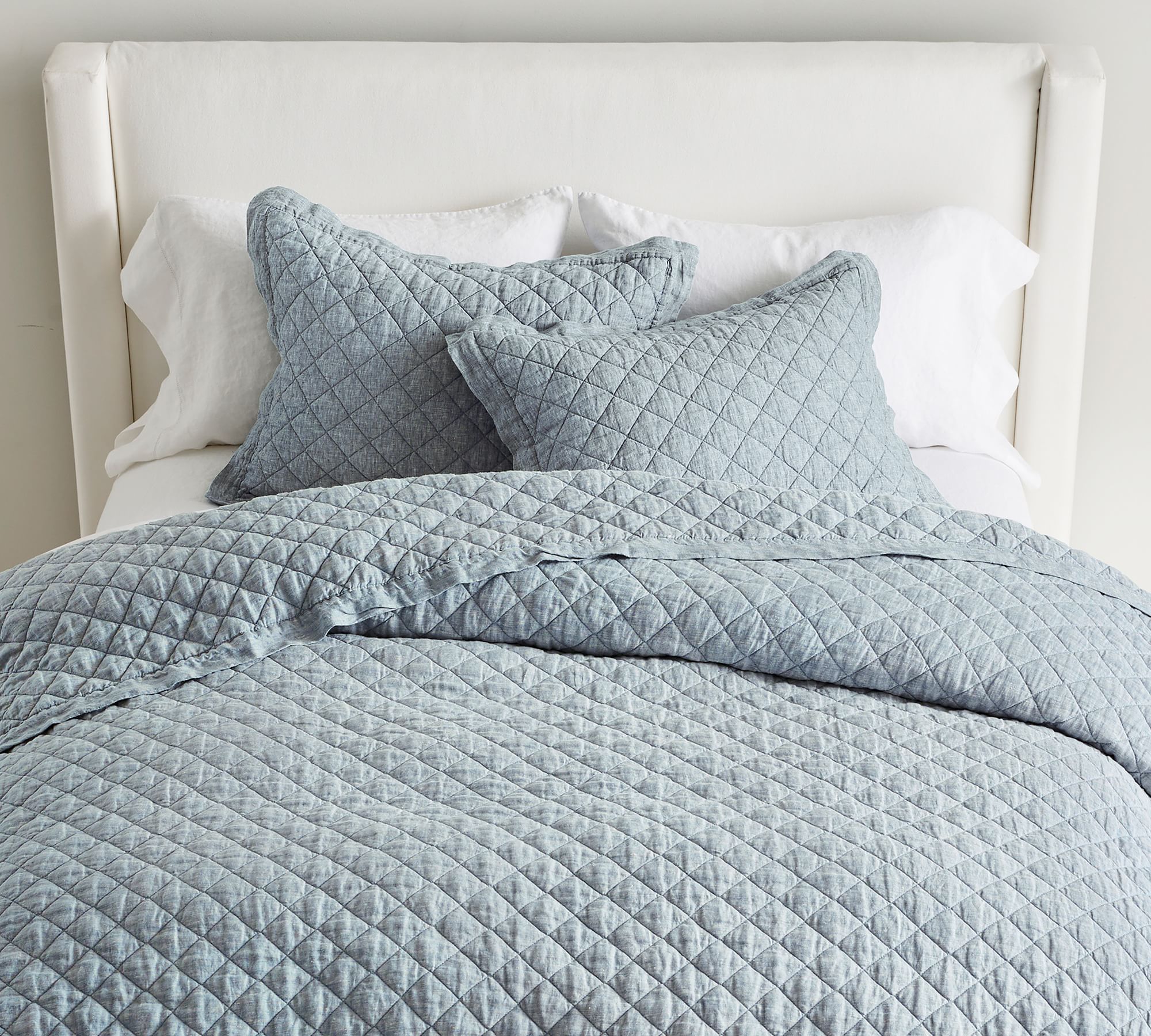 light blue quilt and pillows mixed with all white bedding