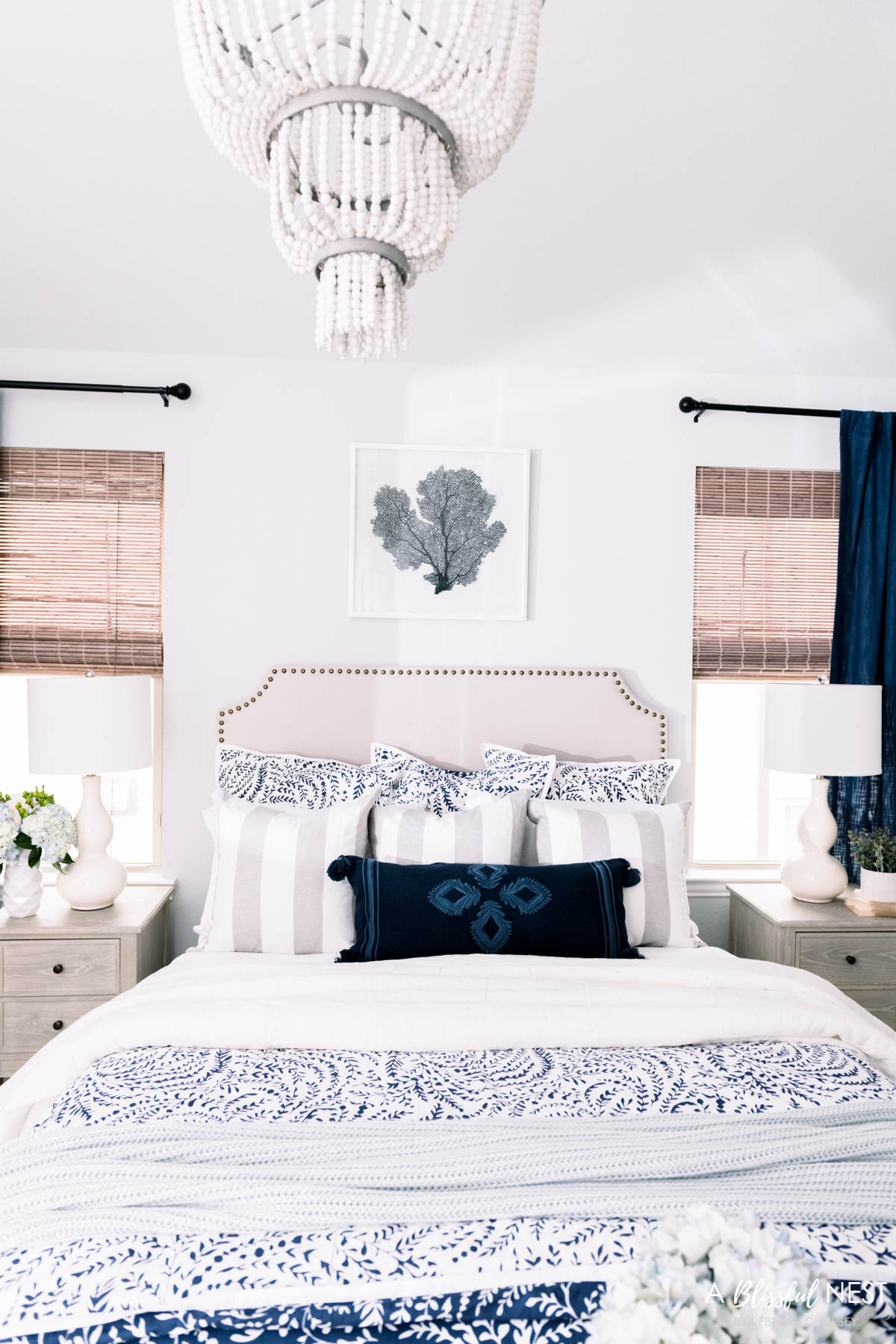 navy and white floral bedding with white sheets, upholstered bed with nailheads, navy window treatments