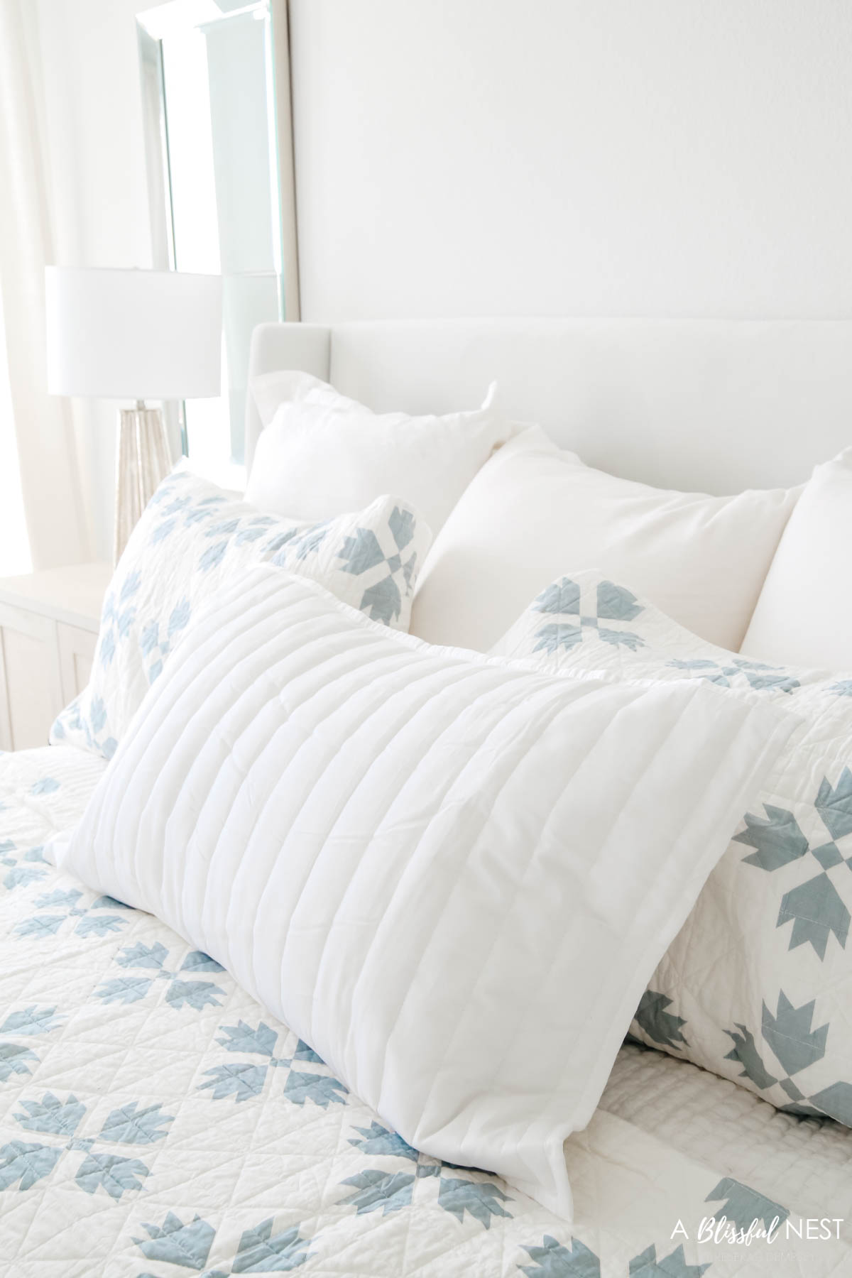 quilted pillows on a white upholstered bed.