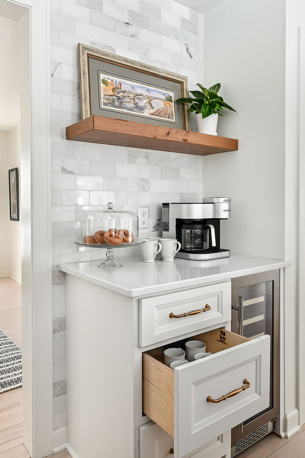 small counter space in a kitchen used for a coffee machine. Drawer below holds coffee mugs