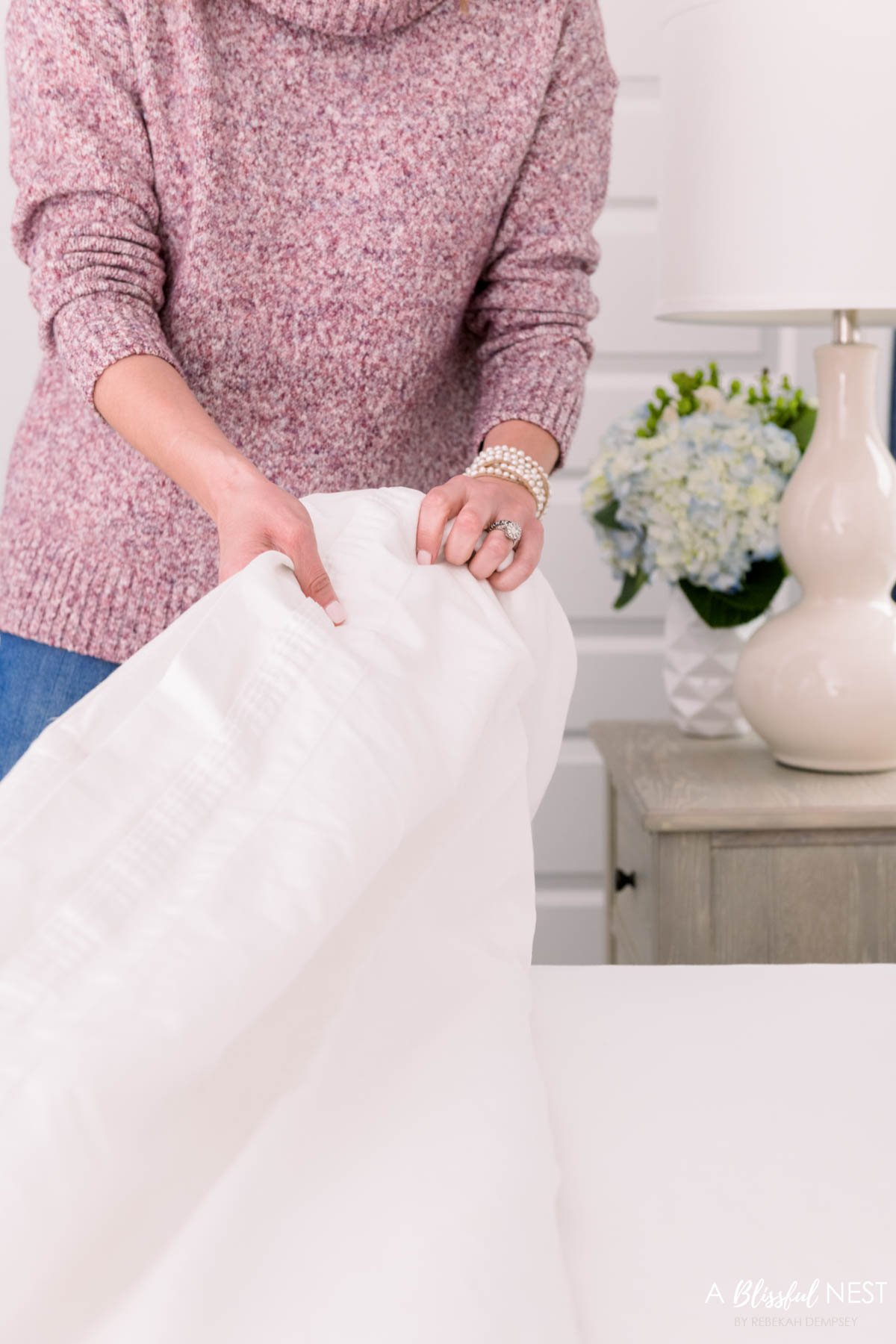white cotton flat sheet being pulled up on a bed