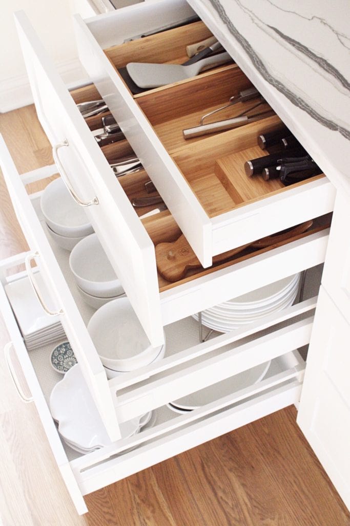 drawers in a kitchen with white dishes 