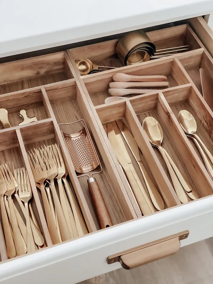 wood drawer dividers separate gold silverware in a kitchen drawer
