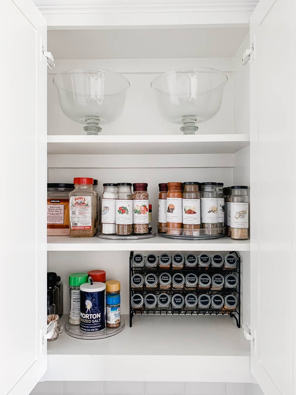 Clear lazy susans and spice rack in a white cabinet