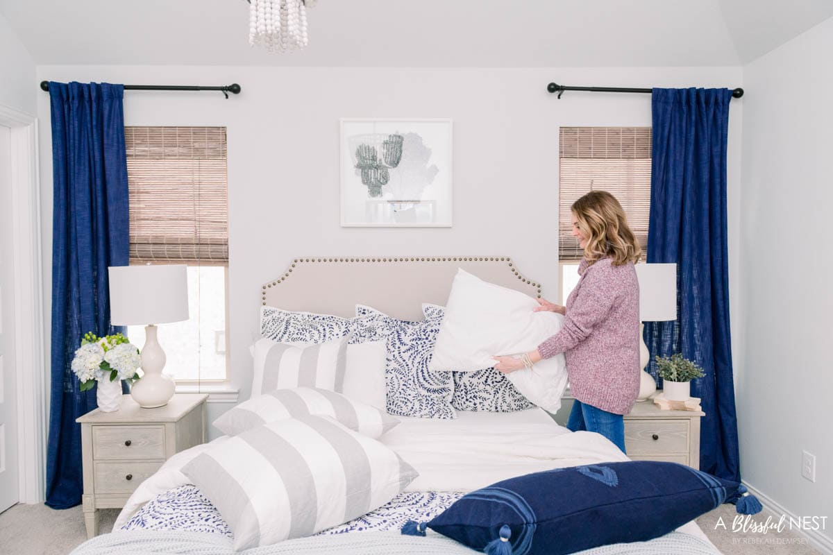 grey and white accent pillows on a bed with navy and white bedding