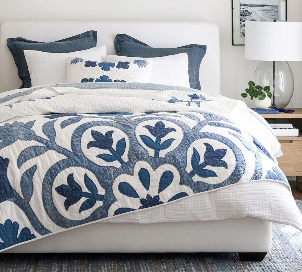 navy and white quilt on a white upholstered bed.