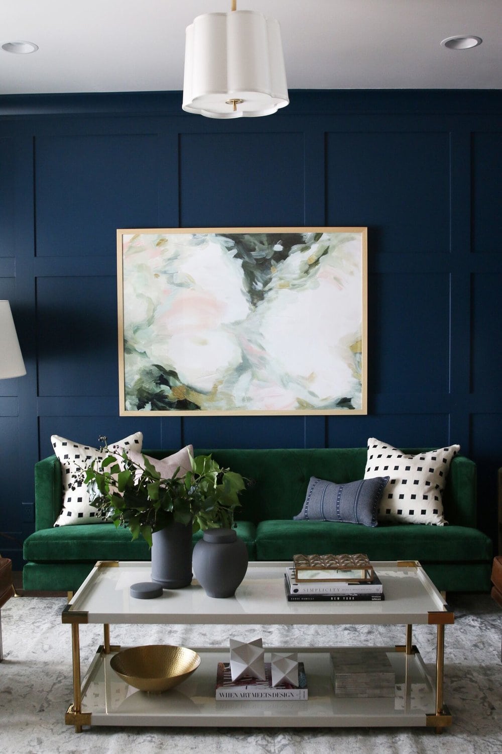 Navy blue board and batten with a emerald green sofa and a large abstract painting on the wall.