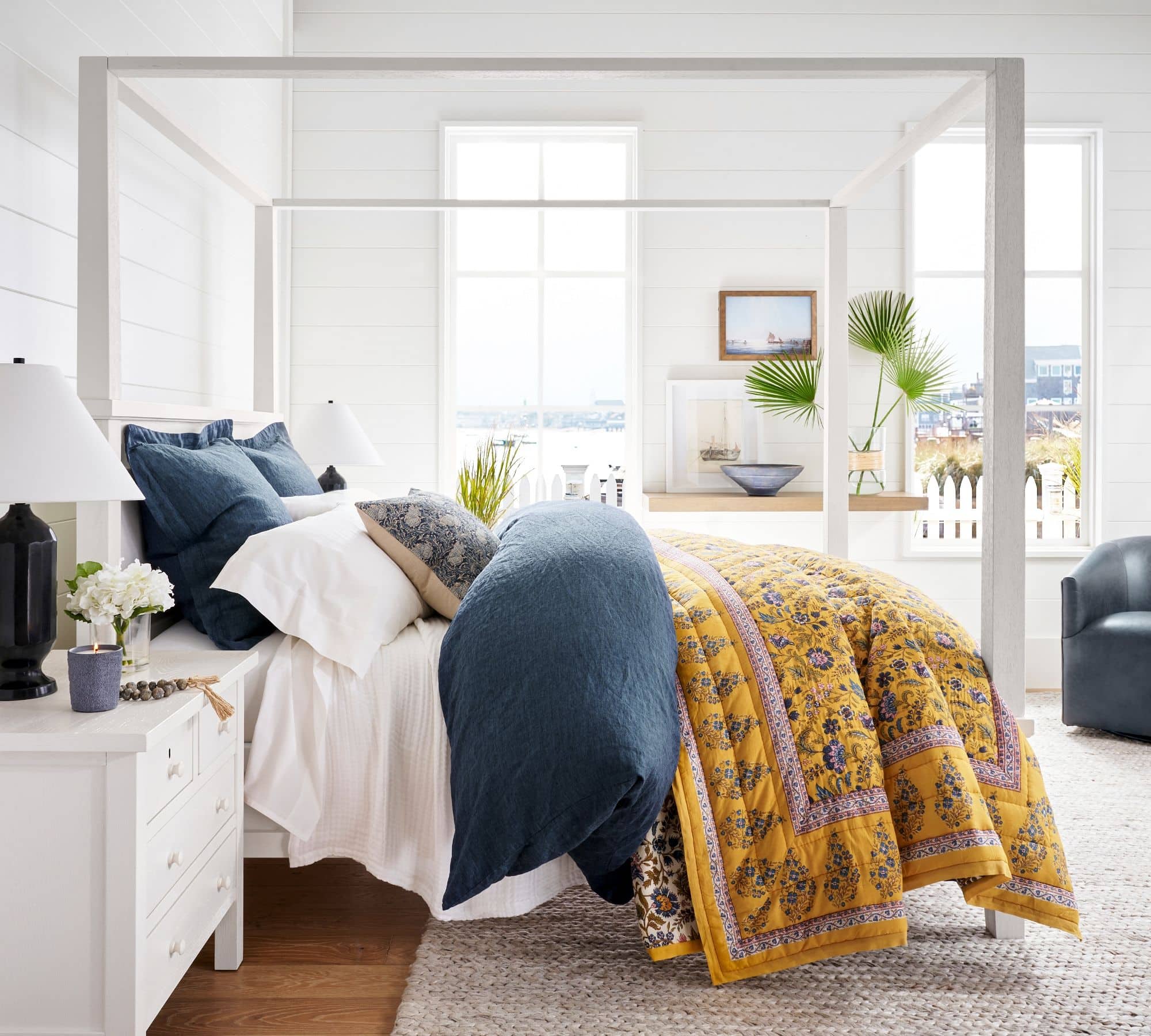 yellow quilt with navy comforter on all white bedding. 