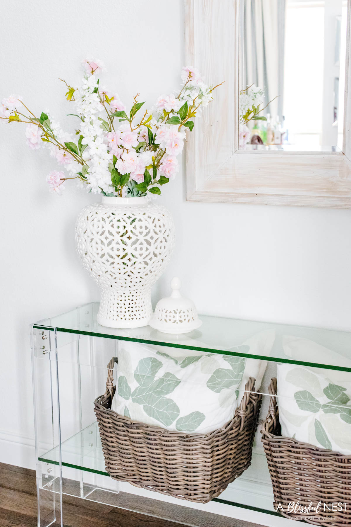 Two baskets under a console table filled with pillows