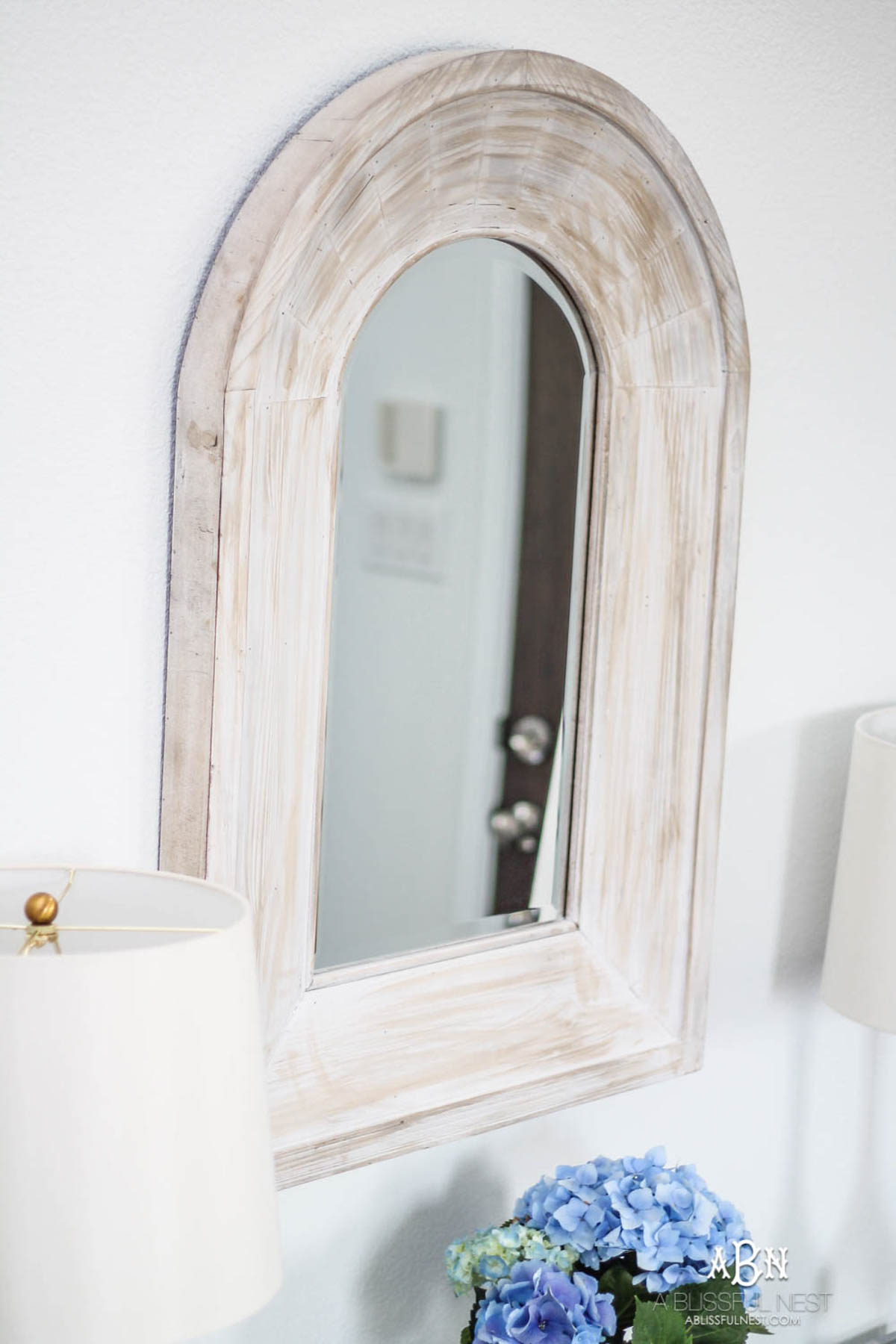 White washed wood mirror above a lucite console table.