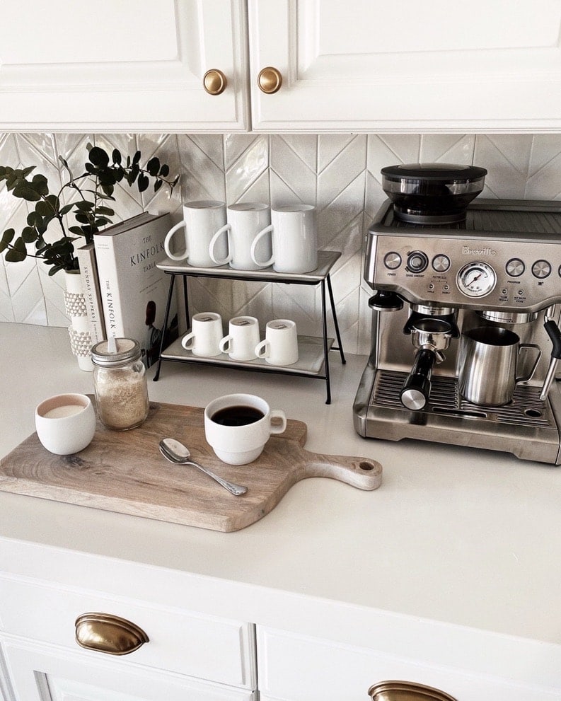 kitchen counter with an espresso machine, tray with coffee mugs, cutting board and cook books.