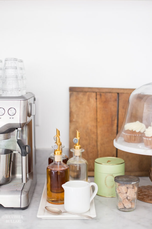 Coffee syrups on a tray with a cake stand and cupcakes